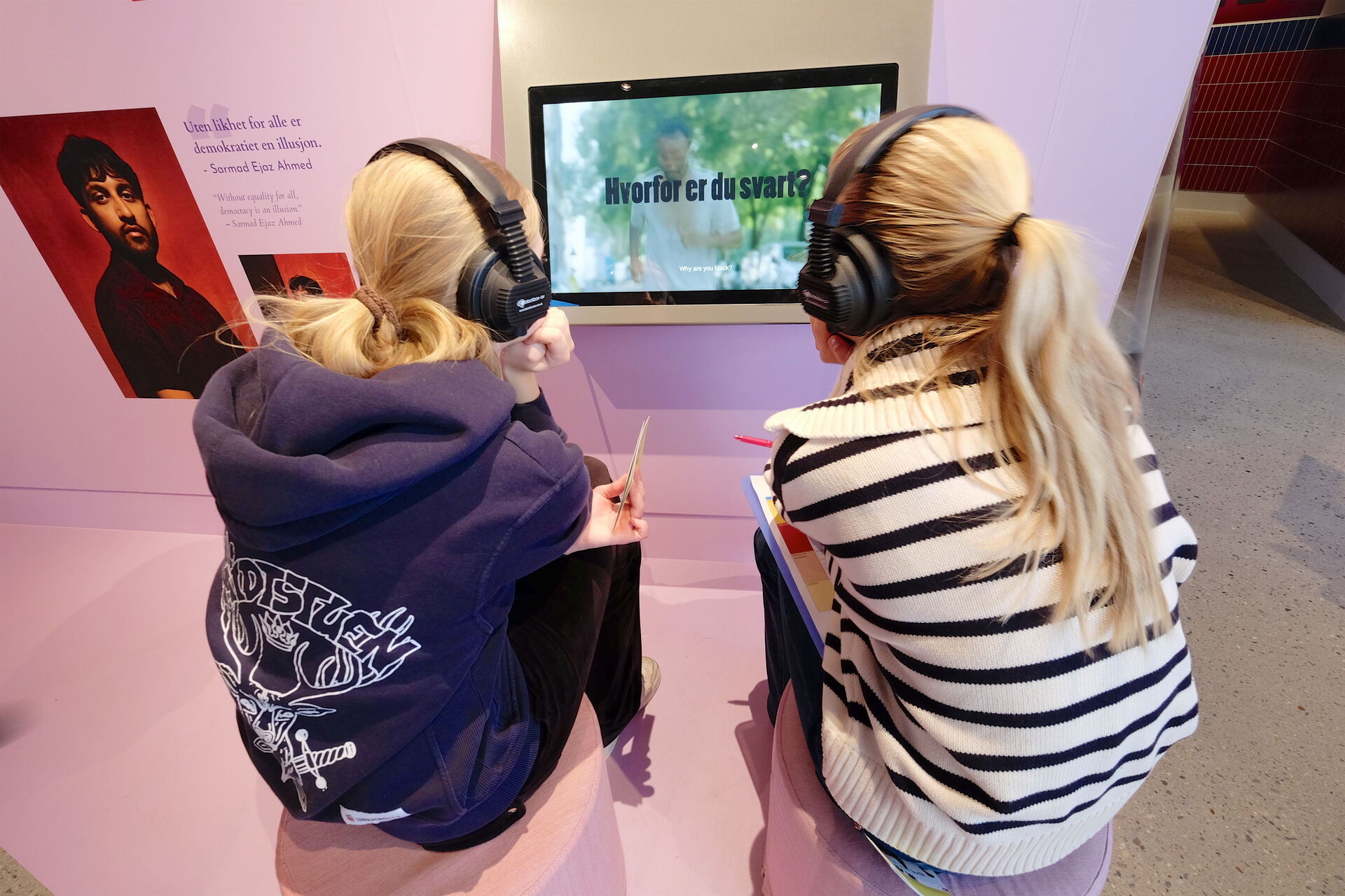 To unge jenter med hestehaler soítter med headset og ser på en skjerm