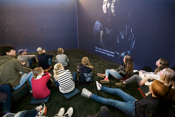 Gruppe ungdommer ser på film i filmrommet til ustillingen U/Synlig - hverdagsrasisme i Norge.