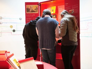 Tre elever fra Hareid Ungdomskole utforsker et arkivskap i utstillingen U/SYNLIG på HL-senteret