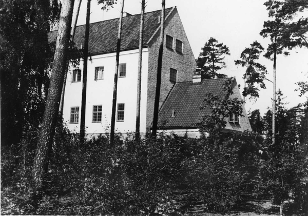 Black and white picture of a building with woods in front