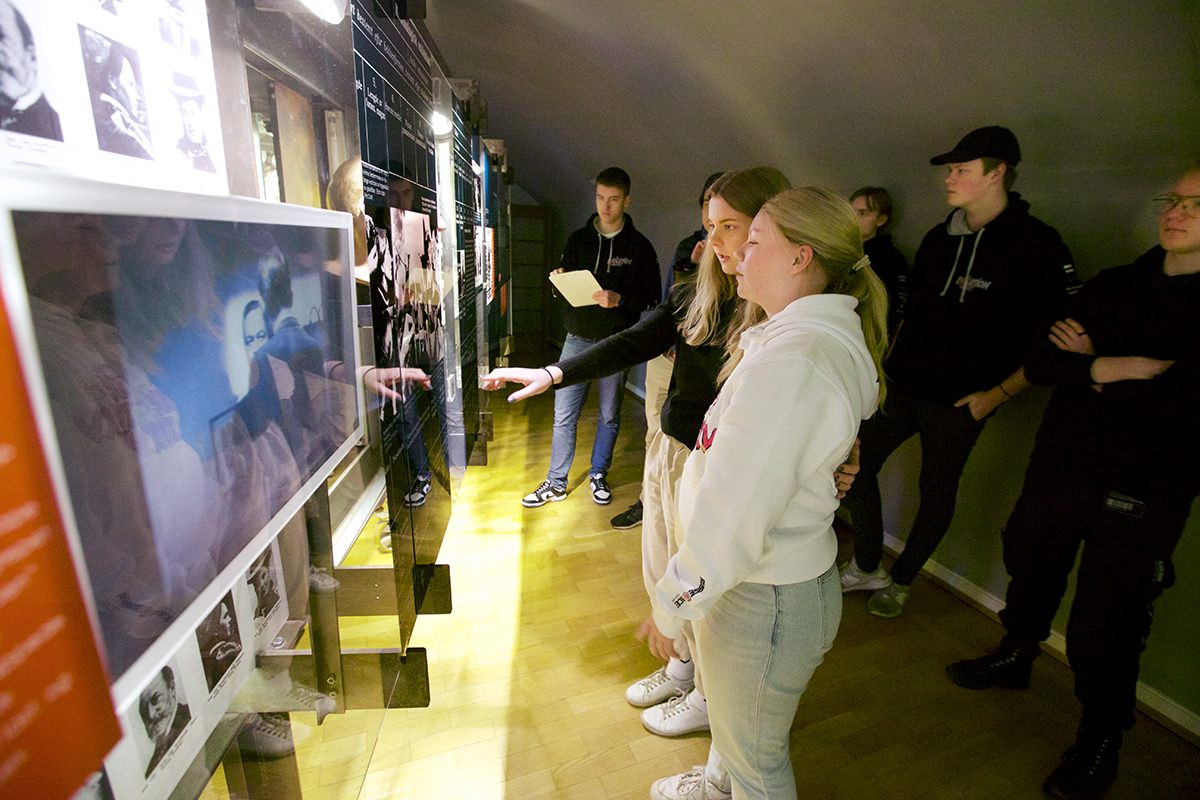 Ungdommer stå og betrakter bilder i en utstilling